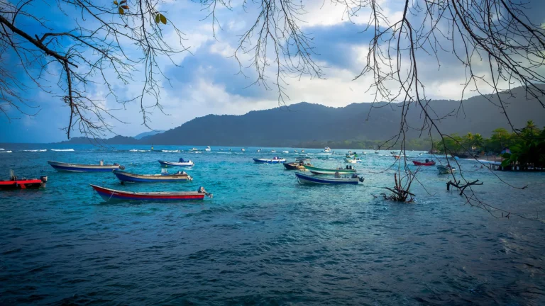 Baía de Capurganá com lanchas coloridas ancoradas perto do muelle e a serra do Darién ao fundo