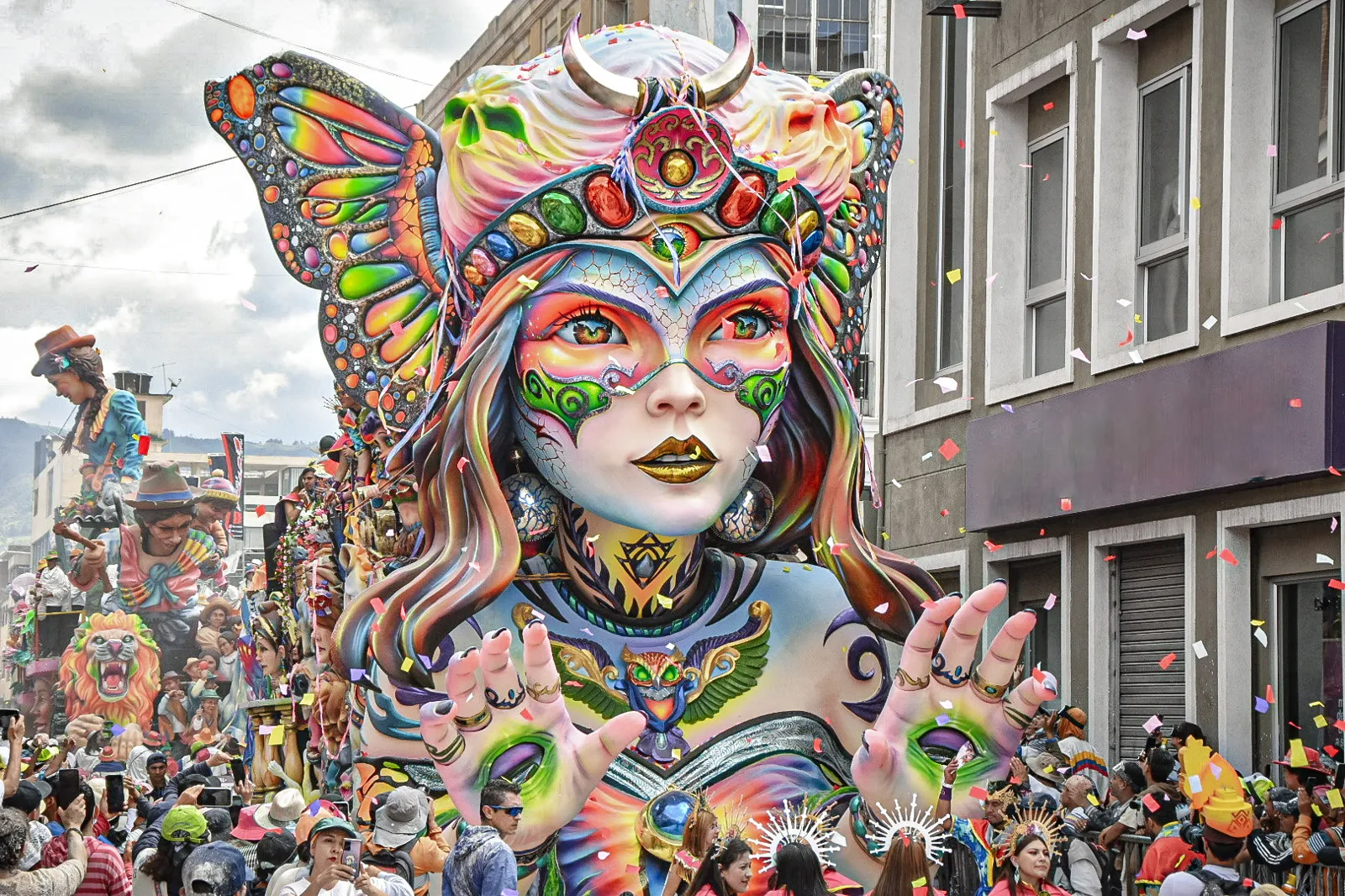 Carro alegórico colorido com figura feminina gigante no desfile do Carnaval de Negros y Blancos em Pasto, cercado de público