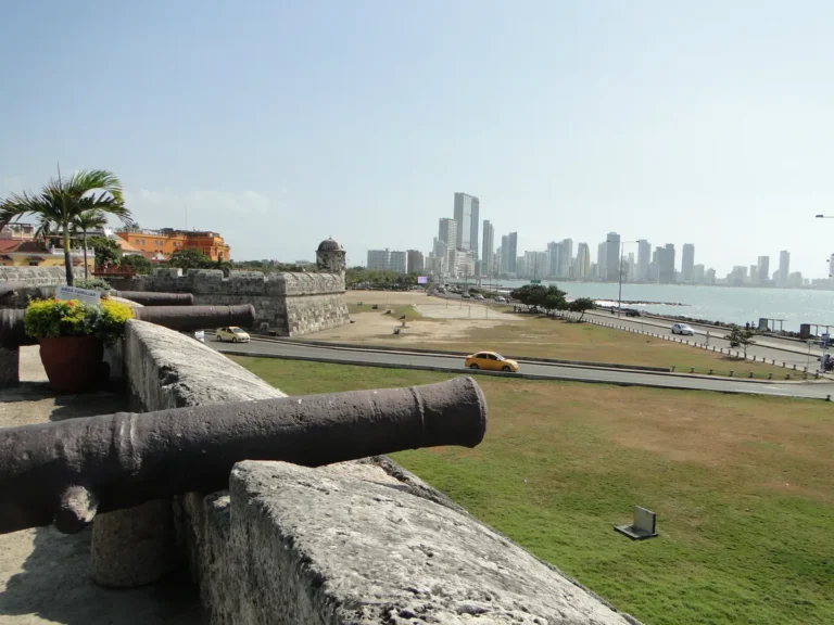 Vista das muralhas de Cartagena, na Colômbia, com canhões antigos em primeiro plano e os prédios de Bocagrande ao fundo, à beira do mar