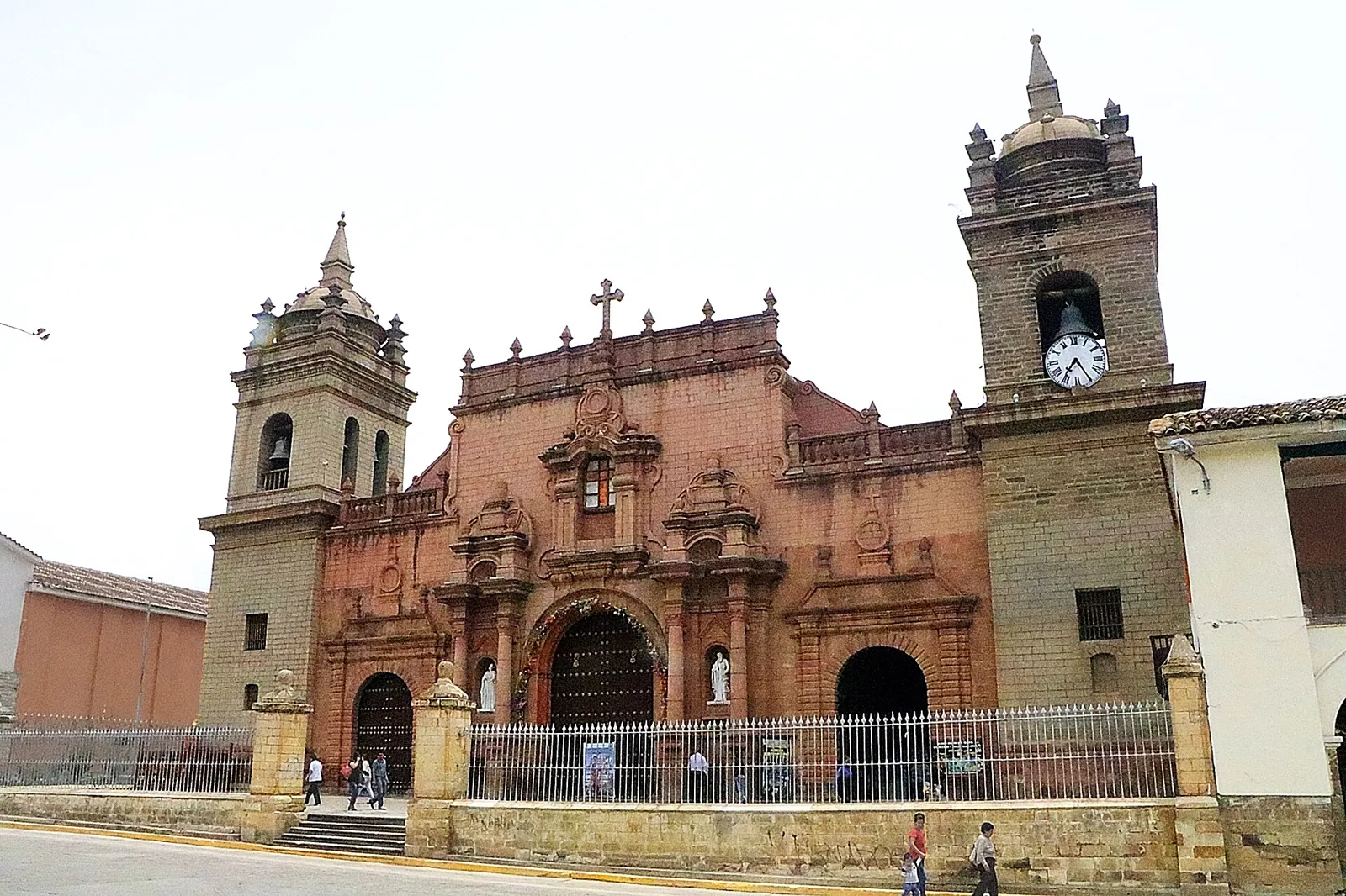 Fachada de pedra rosada da Catedral Basílica de Ayacucho, com duas torres e relógio, em frente à Plaza Mayor de Huamanga