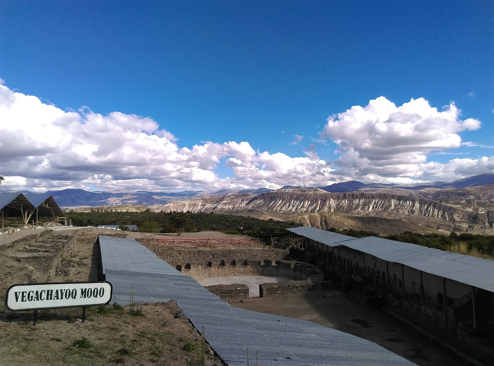 Setor Vegachayoq Moqo do complexo arqueológico Wari, perto de Ayacucho, com coberturas metálicas sobre as escavações e montanhas ao fundo