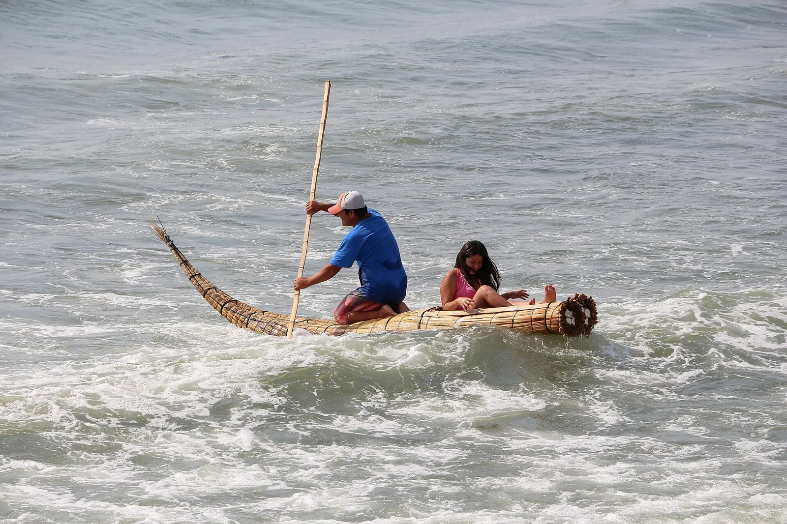 Pescador conduz um caballito de totora nas ondas de Huanchaco, praia vizinha a Chan Chan