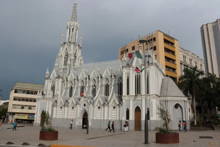 Igreja neogótica branca La Ermita, no centro de Cali, ao lado do Bulevar del Río, com prédios ao fundo