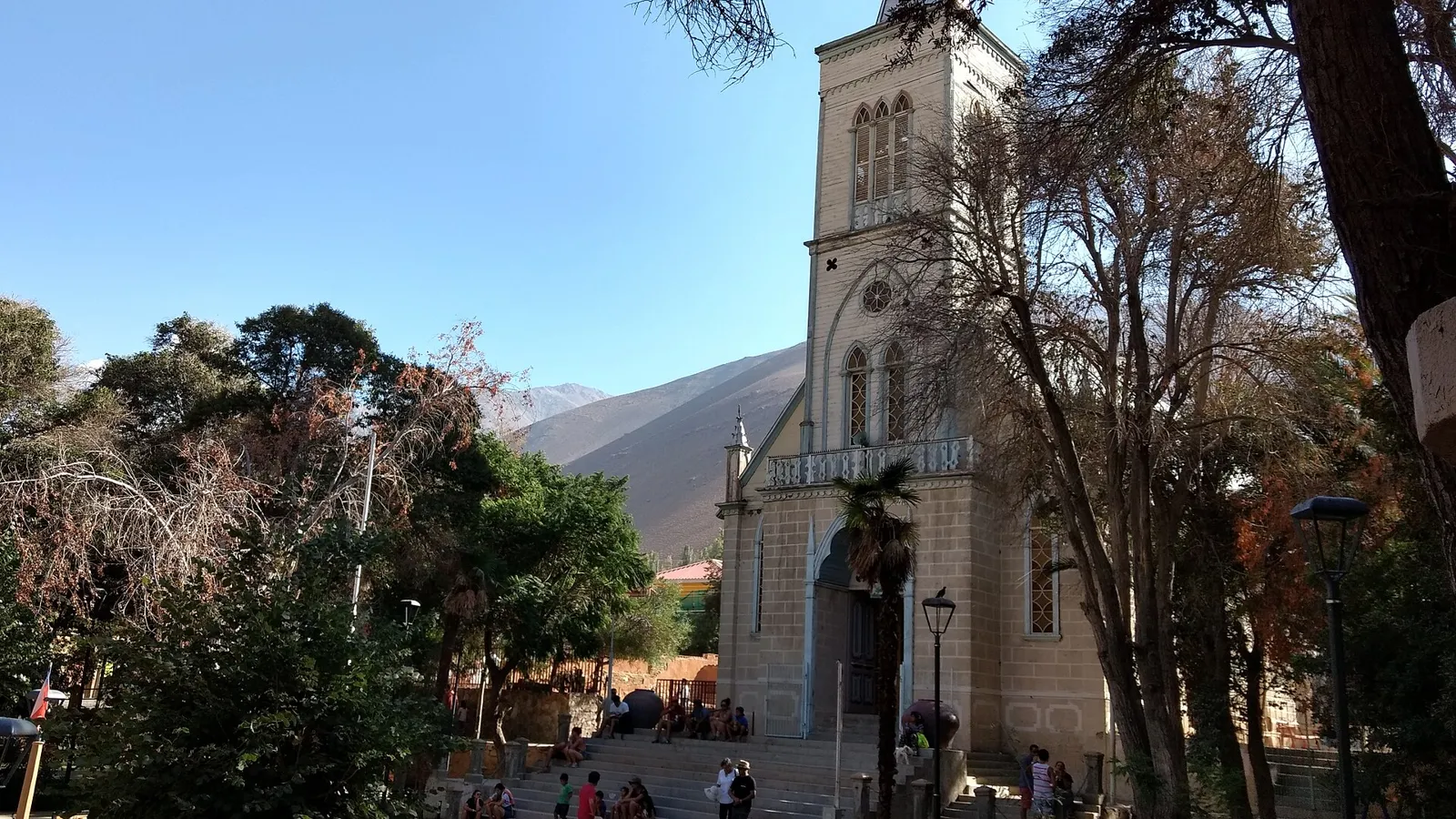 Igreja de Pisco Elqui com torre clara, árvores da praça e montanhas secas do Valle del Elqui