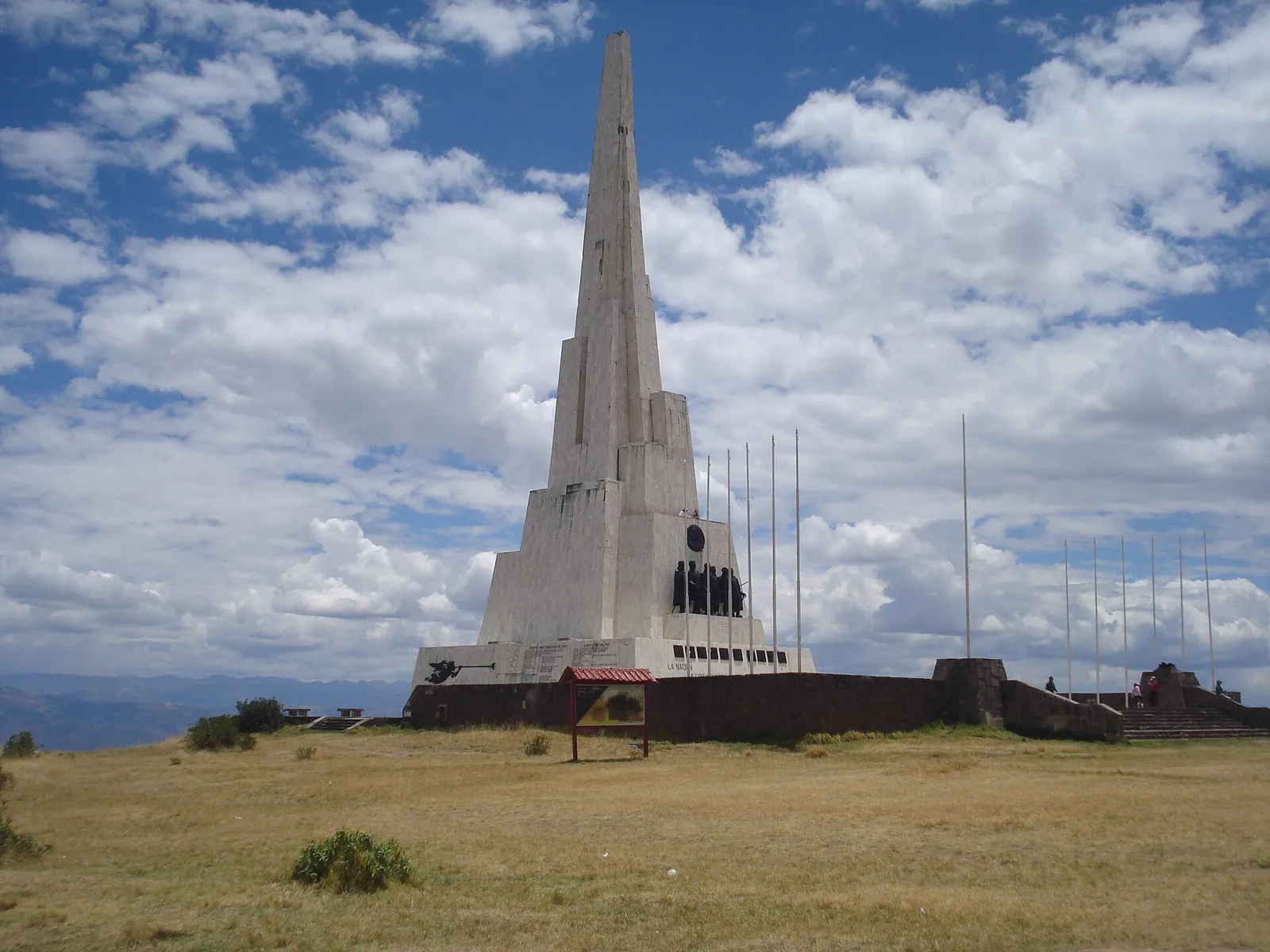 Obelisco branco de 44 metros no Santuário Histórico da Pampa de Ayacucho, em Quinua, sob céu azul com nuvens