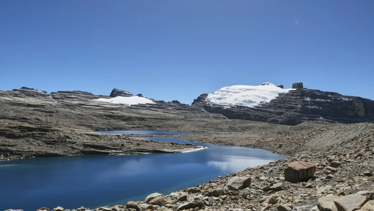 Laguna Grande de la Sierra no Parque El Cocuy, com rochas, lagoa azul e picos nevados da Sierra Nevada ao fundo, Boyacá, Colômbia