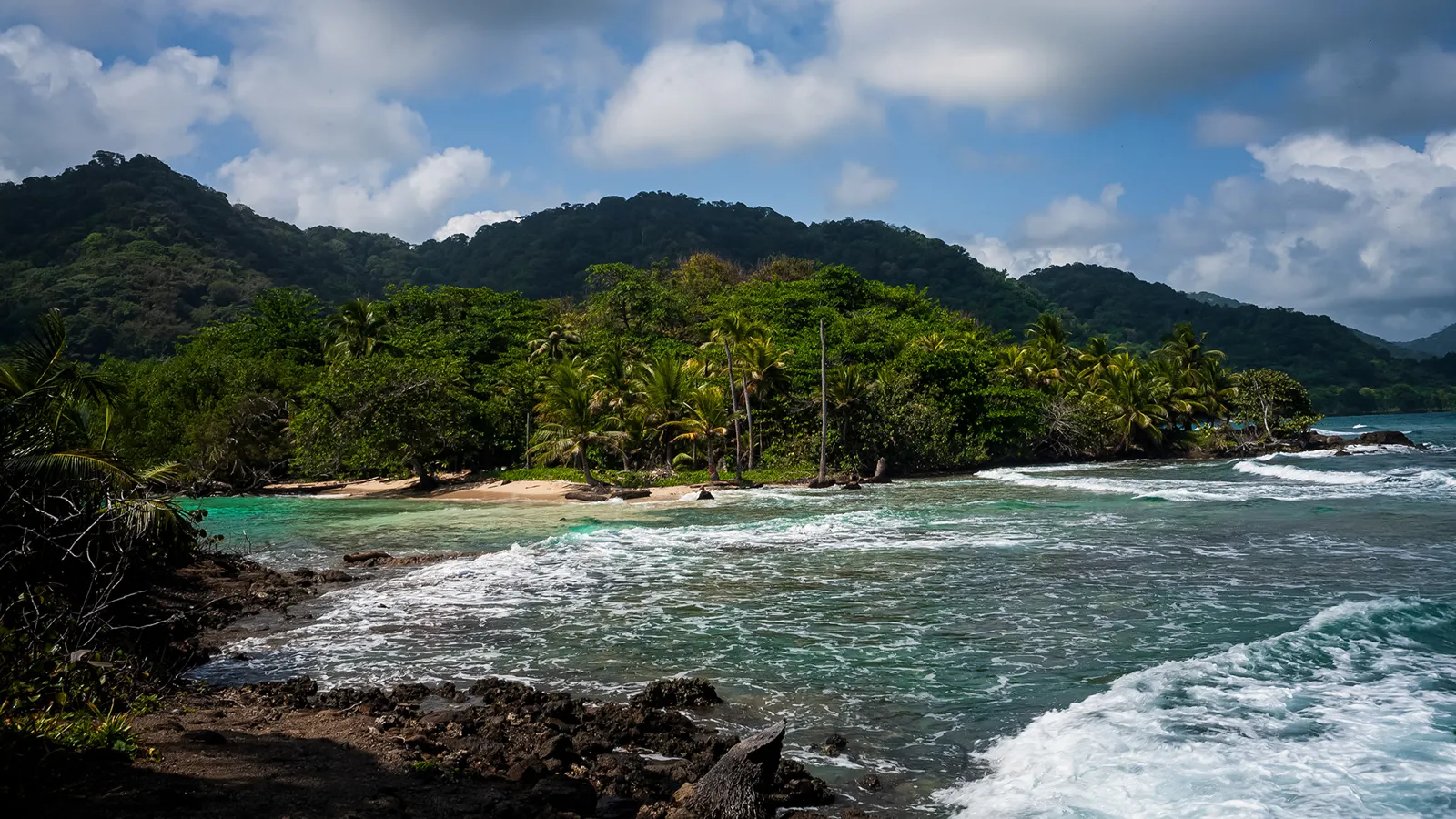 Playa Soledad, nos arredores de Capurganá, com areia clara, ondas e a selva do Darién ao fundo