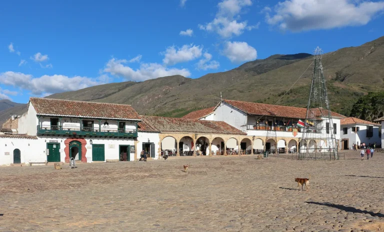 Plaza Mayor de Villa de Leyva, com chão de pedras, casarões brancos de telhado de barro e montanhas ao fundo