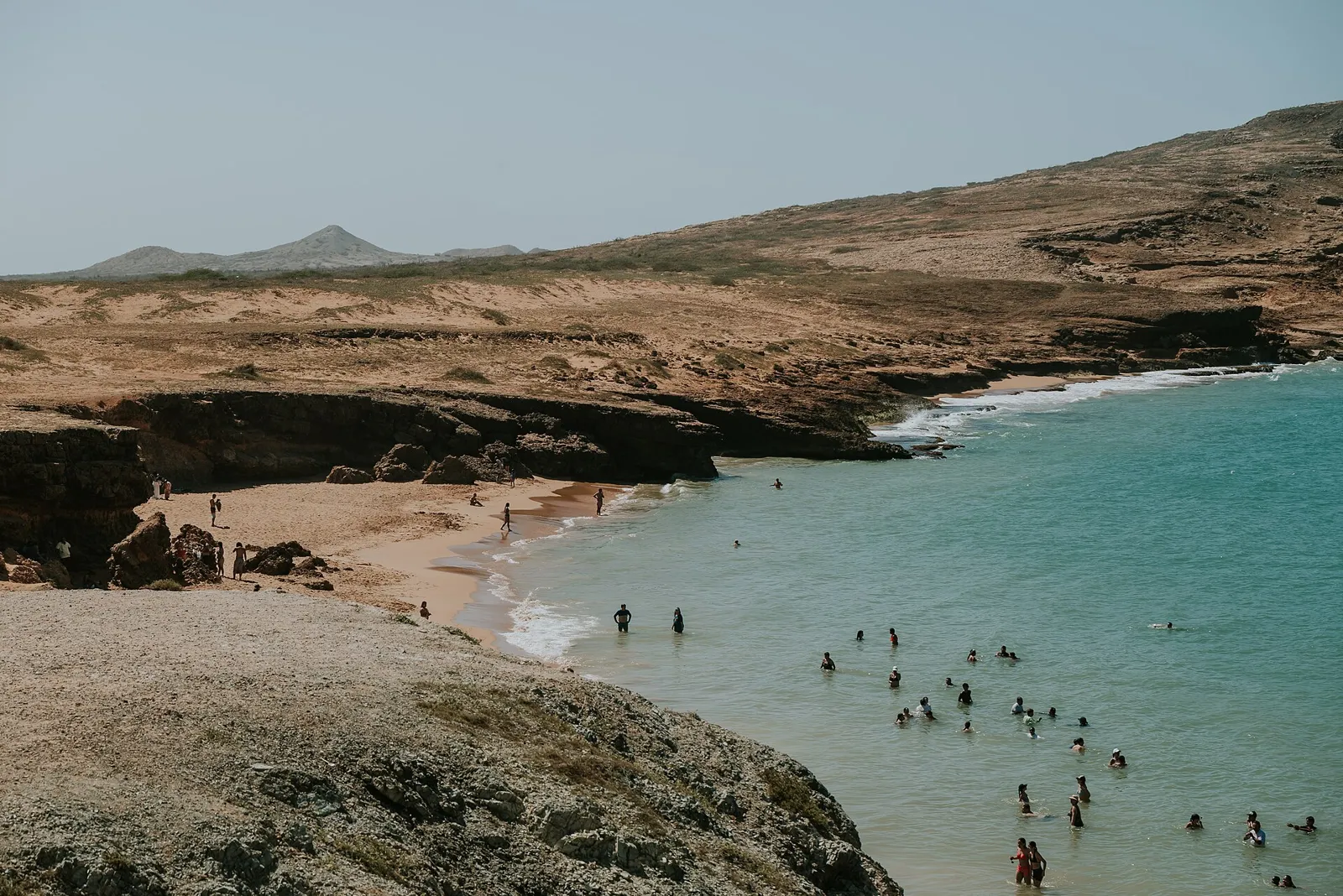 Enseada de água turquesa com banhistas e falésias no Cabo de la Vela, Alta Guajira
