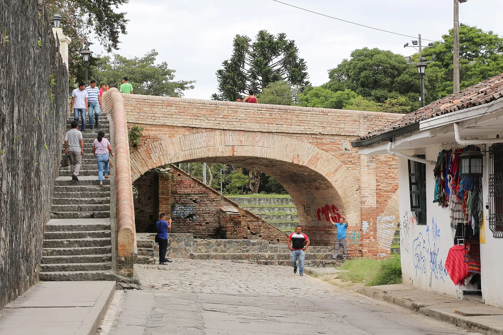 Ponte do Humilladero em Popayán, com arcos de tijolo, escadaria lateral e pedestres na rua de baixo