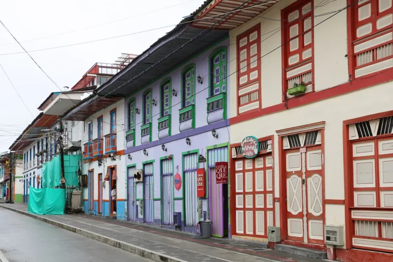 Rua de Filandia, no Quindío, com casarões de sacadas de madeira pintadas em azul, verde e laranja e enfeites coloridos pendurados sobre a rua