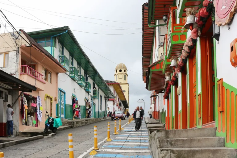 Rua de Salento, no Quindío, com casarões coloridos de sacadas de madeira e a torre amarela da igreja ao fundo